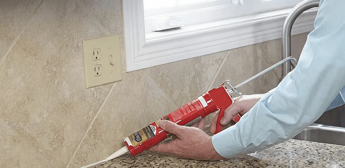Handyman applying caulk along a kitchen backsplash and countertop seam in Los Angeles, CA